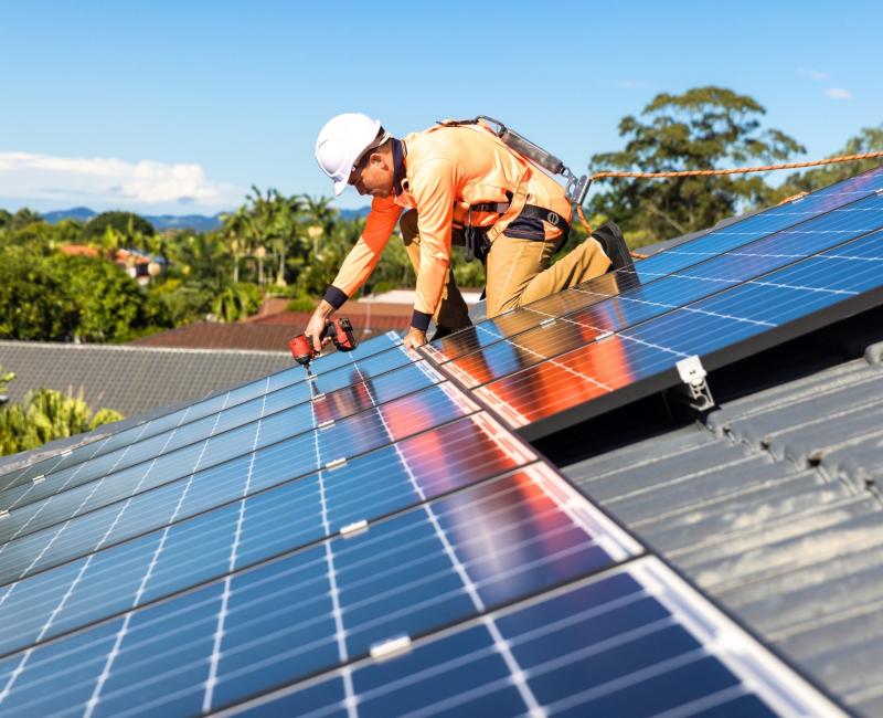 A man installing solar panels on a roof.